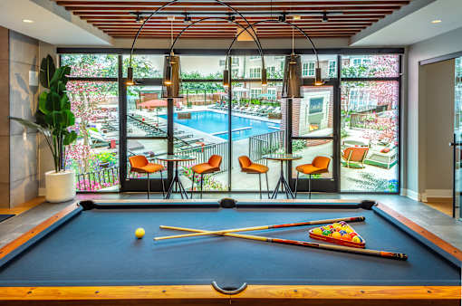 Billiards table with pool area views through floor to ceiling windows at Inwood at Renaissance Square Apartments, Marlton, New Jersey