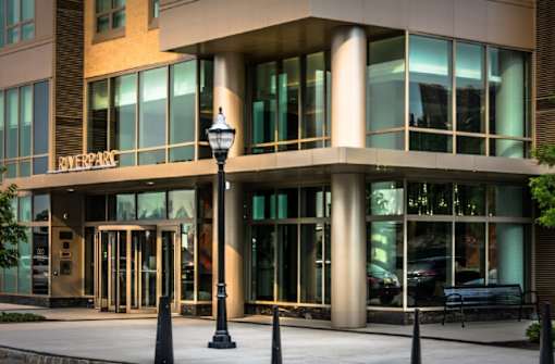 Modern building entrance with glass facade and revolving doors at RiverParc Apartments, Weehawken, 07086