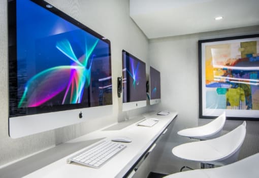 Business center with computer workstations and modern chairs at RiverParc Apartments, Weehawken
