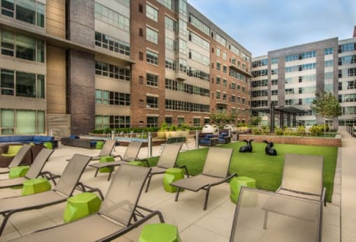 Outdoor courtyard with lounge chairs and green space at RiverParc Apartments, New Jersey, 07086