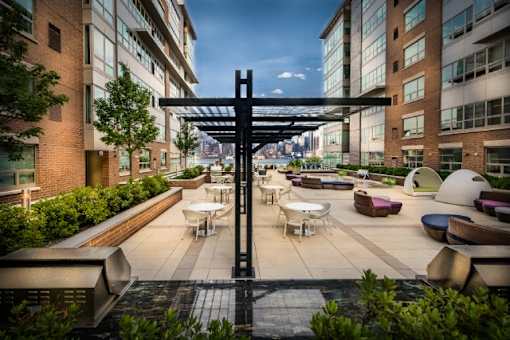 Outdoor courtyard with seating and overhead pergola at RiverParc Apartments, Weehawken, NJ 07086