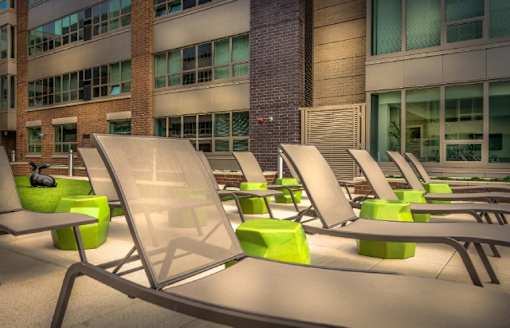 Sundeck with lounge chairs and modern buildings at RiverParc Apartments, Weehawken, NJ