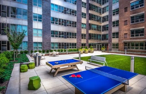 Outdoor courtyard with ping pong tables and seating at RiverParc Apartments, New Jersey