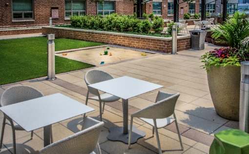 Outdoor patio area with bistro tables and planters at RiverParc Apartments, New Jersey, 07086