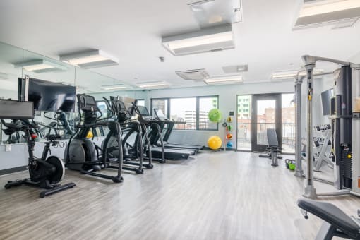 a gym with a lot of exercise machines and a yellow ball in the middle of the room