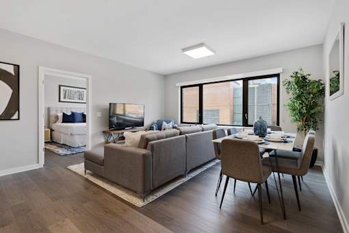 A modern living room with a grey sofa and a dining table set up.