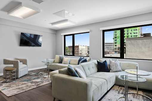 A modern living room with a large couch and a flat screen TV mounted on the wall.