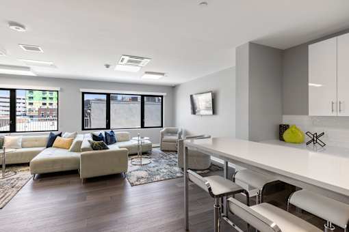 A modern living room with a white sofa and a grey kitchen area.