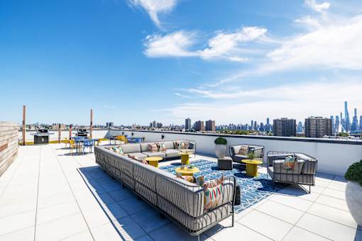 A rooftop patio with a pool and seating area.