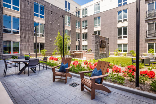 a patio with chairs and tables in front of an apartment building