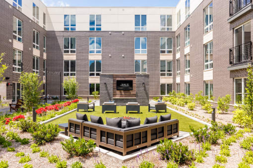 an outdoor area with a couch and chairs in front of an apartment building