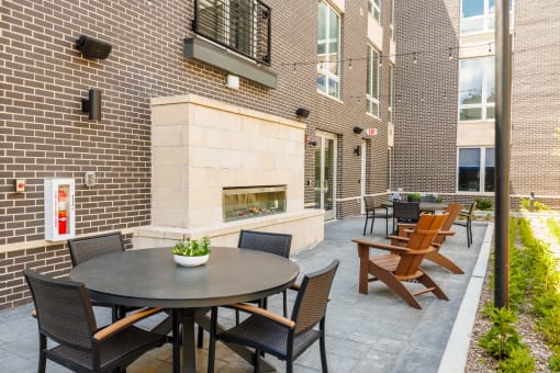 a patio with tables and chairs and a fireplace