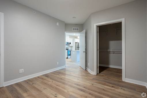 A room with a wooden floor and a doorway leading to another room.