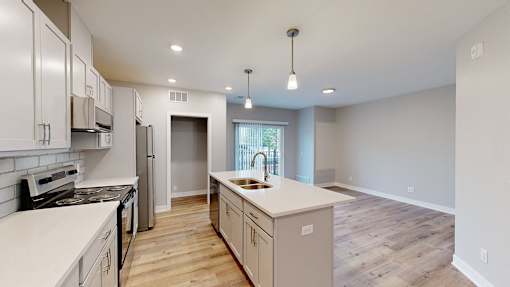 A kitchen with white countertops and wooden floors.