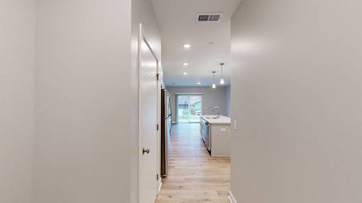 A long hallway with a kitchen at the end.