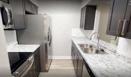 Modern renovated kitchen with stainless steel appliances, new cabinets, countertops, and luxury vinyl flooring in a 2-bedroom unit at Lynnhaven Landing