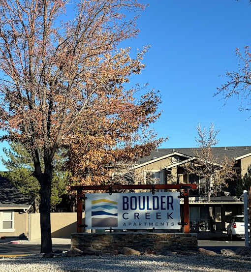A sign for Boulder Creek Apartments is in front of a building.