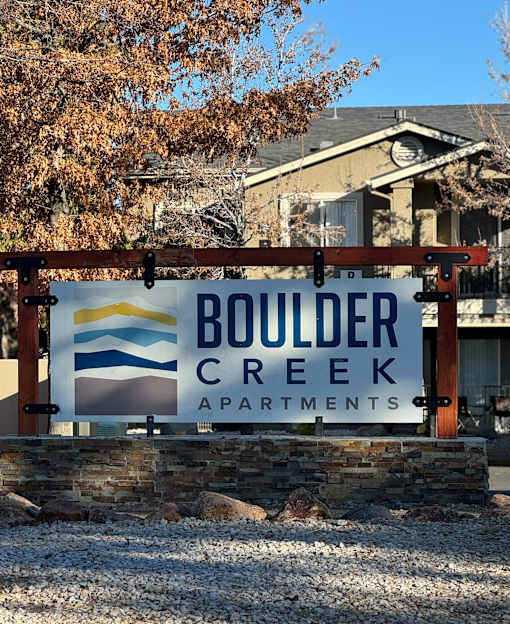 A sign for Boulder Creek Apartments is displayed in front of a building.