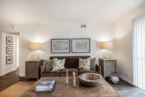 A living room with a brown couch and two lamps.