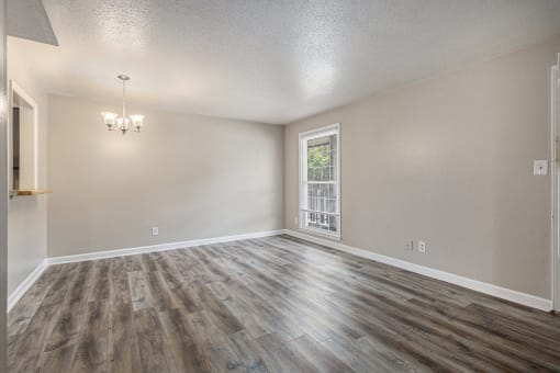 an empty living room with wood flooring and a window