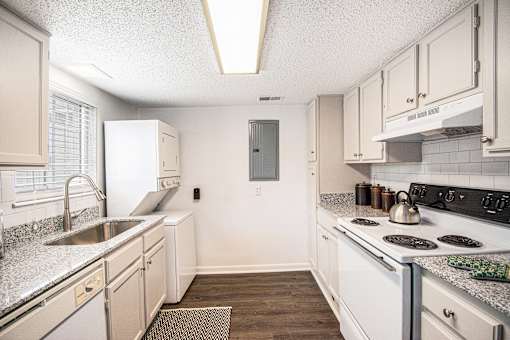 A kitchen with white appliances and wooden floors.