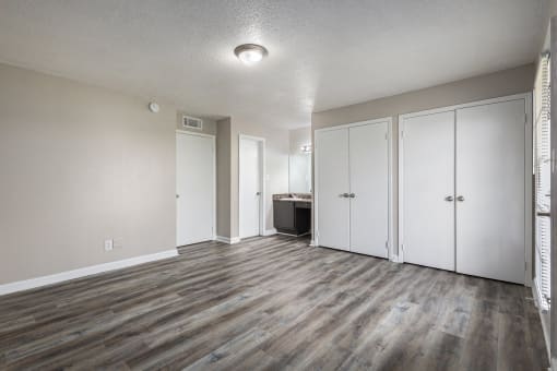 an empty living room with wood floors and white closets
