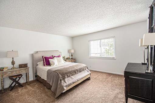 A bedroom with a bed, nightstand, and window.