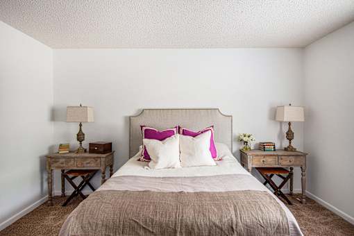 A bedroom with a bed, two nightstands, and a lamp.