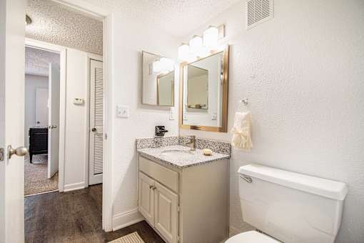 A bathroom with a white toilet, sink, and mirror.