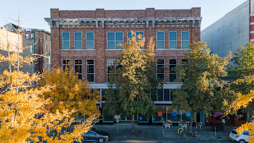A black car is parked in front of a brick building.