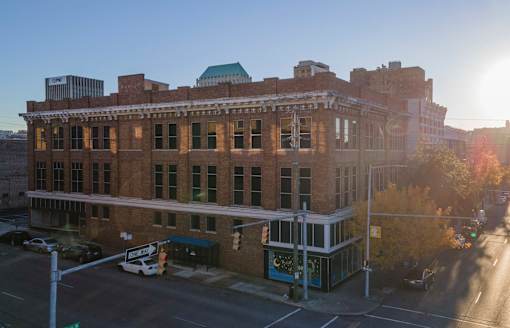 A large brick building with a green roof and a white car parked in front.