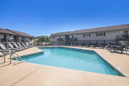 A swimming pool surrounded by lounge chairs and buildings.