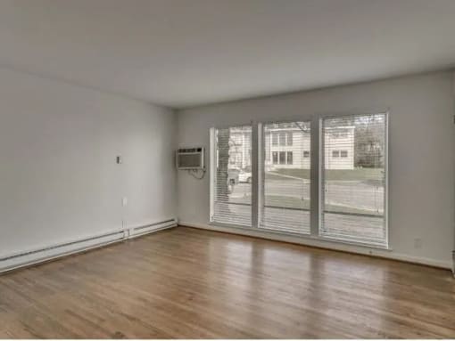 an empty living room with a large window and wooden floors
