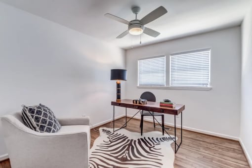 a living room with a couch and a desk with a ceiling fan