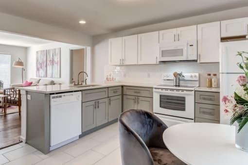 a white kitchen with white appliances and a table