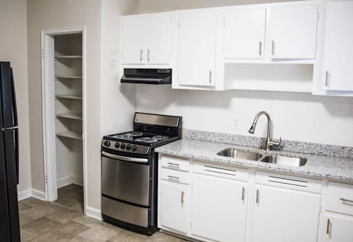 A kitchen with white cabinets and a black stove top oven.