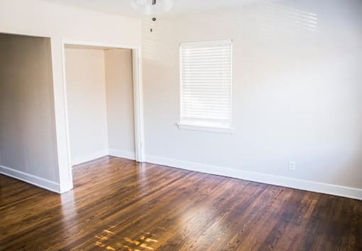 A room with wooden floors and a window with blinds.
