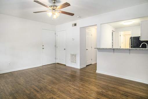 A room with a ceiling fan and wooden floors.