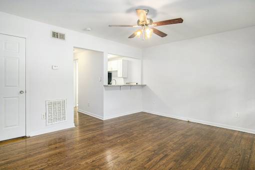 A room with a ceiling fan and wooden floors.