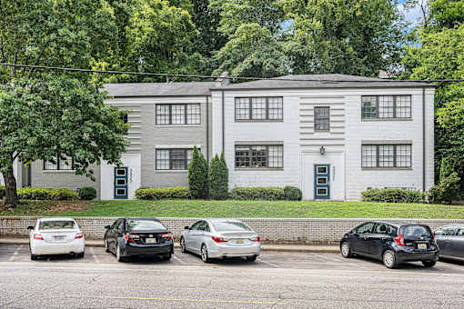 A grey building with a black door and a green lawn in front.