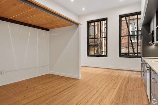 A room with wooden floors and a window with bars on it.