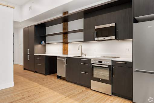 A modern kitchen with dark wood cabinets and stainless steel appliances.