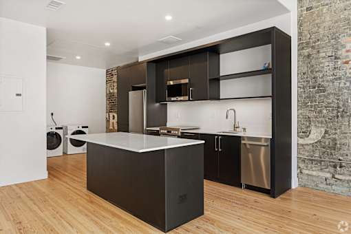 A modern kitchen with a large island and dark wood cabinets.