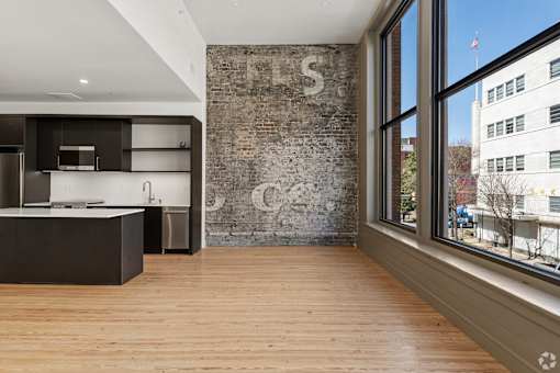 A kitchen with a wooden floor and a brick wall with a letter S on it.