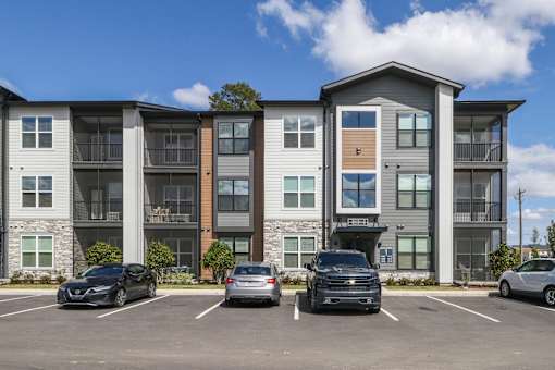 A row of townhouses with cars parked in front.at The Liliana Apartment Homes, Pooler Georgia