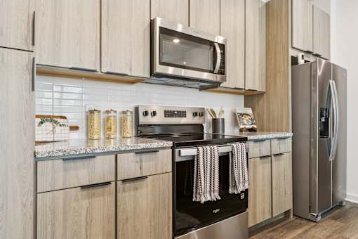 A modern kitchen with wooden cabinets and stainless steel appliances.at The Liliana Apartment Homes, Pooler, GA 31322