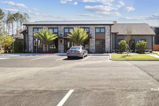 A car is parked in a parking lot in front of a building.at The Liliana Apartment Homes, Pooler