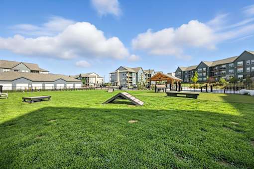 A park with a grassy area and benches in front of apartment buildings at The Garrison Luxury Apartment Homes, Fountain, CO 80817