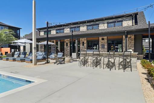 A poolside area with lounge chairs and a building in the background.at The Liliana Apartment Homes, Georgia
