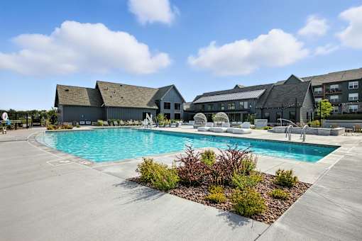 A large outdoor swimming pool surrounded by buildings and plants at The Garrison Luxury Apartment Homes, Fountain, CO 80817